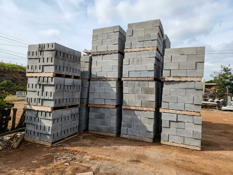 Fileiras de paletes com blocos de concreto empilhados em um pátio.