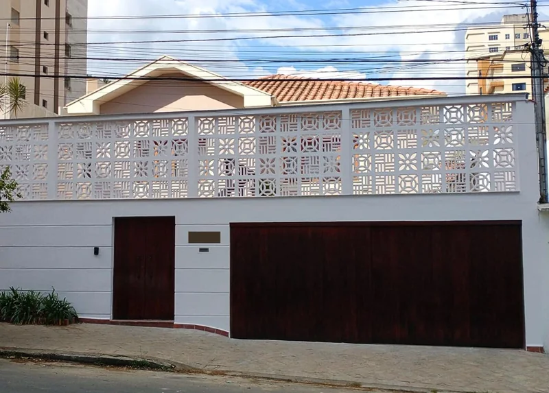 Cobogós de diferentes desenhos formando um painel acima dos portões de uma casa.