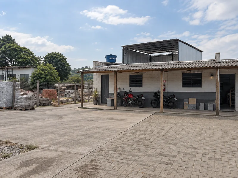 Fachada com área coberta, motocicletas e pátio pavimentado.
