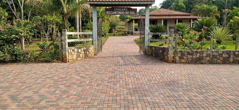 Piso intertravado em tons cinza e avermelhados no acesso a uma propriedade com jardim.