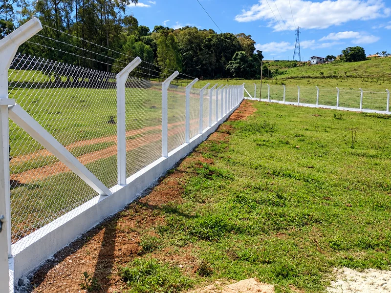 Alambrado com mourões de concreto e apoio diagonal delimitando um terreno gramado